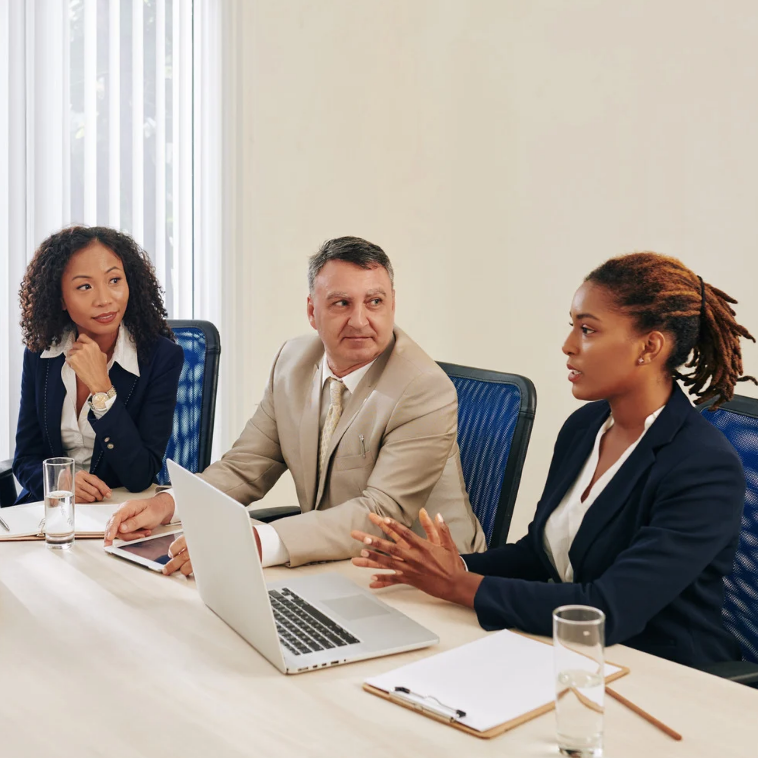 Three professionals in a meeting, listening and engaging with one another.
